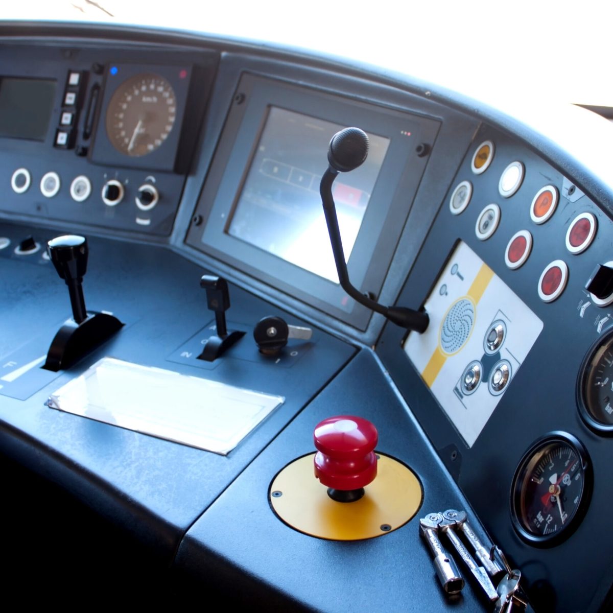 Red button of emergency brake and keys from the door of the train lying on the control panel in the cabin of train